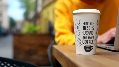 Closeup paper cup with coffee on table outdoor with person networking on laptop  스톡 동영상 132258118
