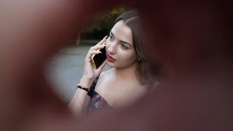 Closeup peeping through gap for young beautiful woman talking on phone on street Stock Footage 138040858