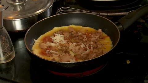 Closeup of pepper grinder adding flavour to cooking omelette on stove top, Stock Footage 128451608