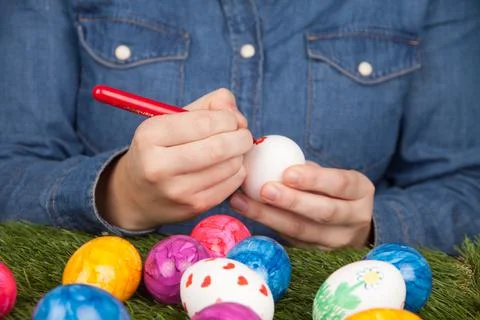 Closeup of a person drawing patterns on eggs with markers for Easter 스톡 사진