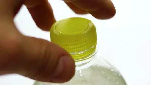 Closeup of person's hand closing yellow plastic water bottle on white background Stock Footage 247435595
