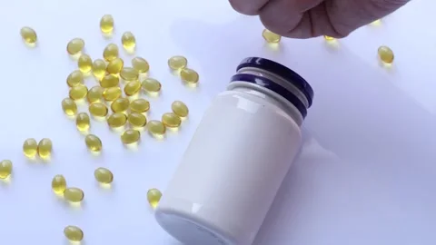 Closeup of persons hand selecting a vitamin d capsule from surface near Video stock 310783721