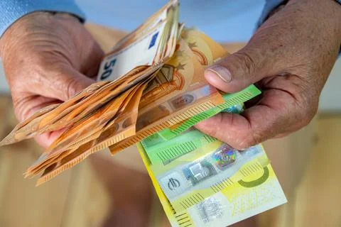 A closeup of a persons hands holding a stack of Euro bills. The bills are f.. Stock Photos