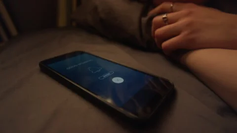 Closeup Phone on Bed with Alarm Icon on Screen Stock Footage 329654119