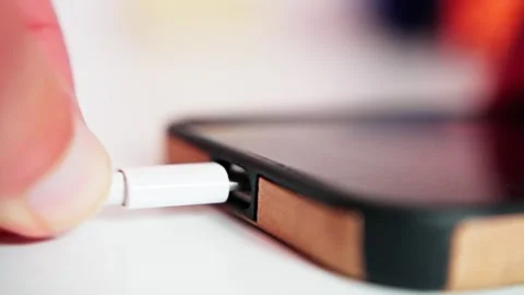 Closeup phone charging cable being plugged into smartphone port by fingertip Stock Footage 321611994