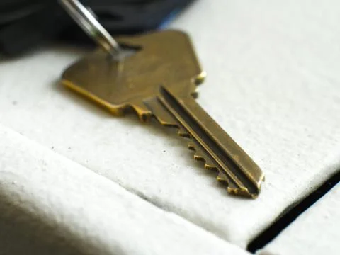 Closeup photograph of a used old triangular shaped brownish yellow house key  스톡 사진