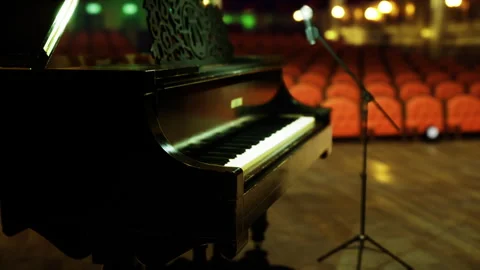 Closeup of piano and microphone with empty seats in warmlit auditorium Stock Footage 340661826
