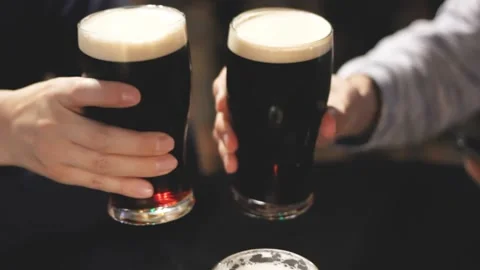 Closeup pints of draft beer toast in a pub, male hands with mugs in dark scene 스톡 동영상 139831091