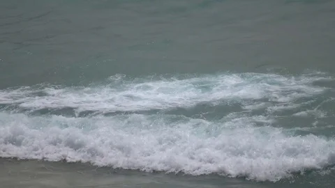 Closeup plan view of seascape with arriving waves crashing on sandy shore. 4K Stock Footage 72706085