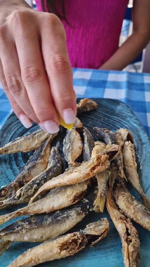 Closeup plate of fried horse mackerel fish on the table in a restaurant and a wo Stock Footage 285247994