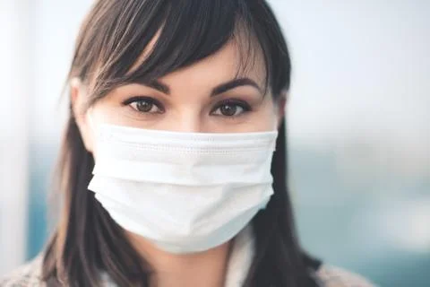 Closeup up portrait of adult woman wearing medical mask outdoors. Looking at  Stock Photos