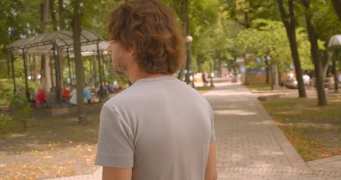 Closeup portrait by camera moving around caucasian man standing in park outdoors Video stock 114922542