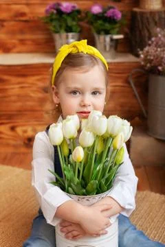 Closeup portrait of little girl with bouquet of white tulips sitting in garden Stock Photos