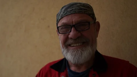 Closeup portrait of a smiling gray-bearded man with glasses and a headband Stock Footage 101689400