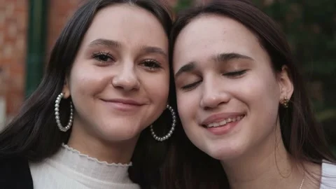 Closeup portrait of two young beautiful smiling teenage girls posing on street Video stock 231037846