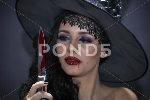 Closeup portrait of woman with bloody knife in her hand in the dark Stock Photos
