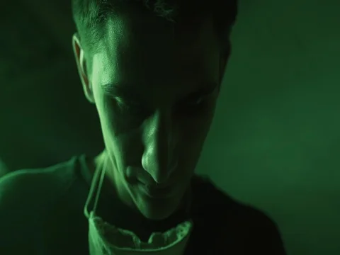 Closeup Portrait of young crafter under green neon light in the dark workshop. Stock Footage 73664032