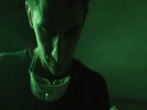 Closeup Portrait of young crafter under green neon light in the dark workshop. Stock Footage 73664448