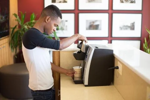 Closeup portrait, young guy making hot or iced coffee with machine, isolated  Stock Photos