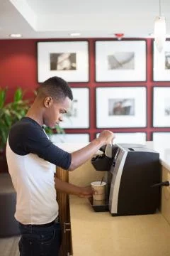 Closeup portrait, young guy making hot or iced coffee with machine, isolated  Stock Photos