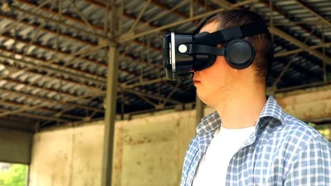 Closeup portrait of young man using VR glasses outdoor with old building exterio Stockbeeldmateriaal 116795971