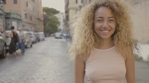Closeup portrait of a young mixed race woman smiling in the street Stock Footage