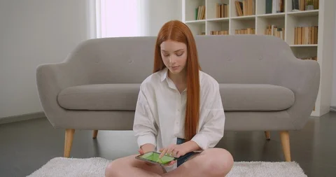 Closeup portrait of young pretty redhead female using the tablet and showing Video stock 112667077