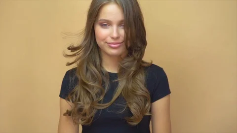 Closeup portrait of young wooman posing to a camera with blowed out hair on grey Stock Footage 114738930