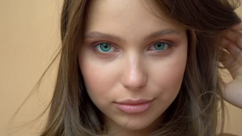 Closeup portrait of young wooman posing to a camera with blowed out hair on grey Stock Footage 114739477