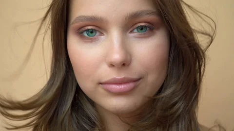 Closeup portrait of young wooman posing to a camera with blowed out hair on grey Stock Footage 114739614