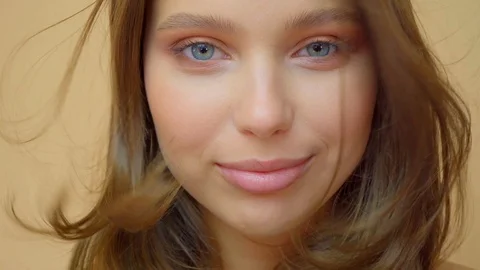 Closeup portrait of young wooman posing to a camera with blowed out hair on grey Stock Footage 114739663