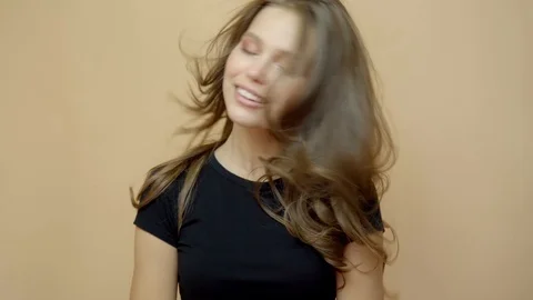 Closeup portrait of young wooman posing to a camera with blowed out hair on grey Stock Footage 114741062