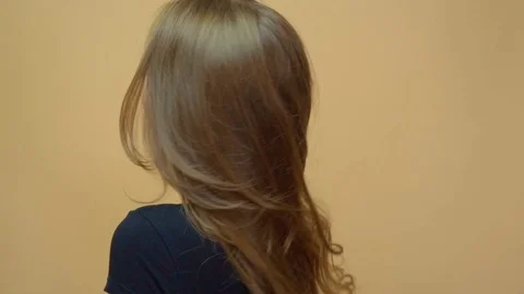 Closeup portrait of young wooman posing to a camera with blowed out hair on grey Stock Footage 114741205