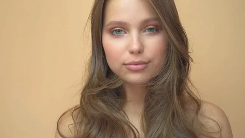 Closeup portrait of young wooman posing to a camera with blowed out hair on grey Stock Footage 114741880
