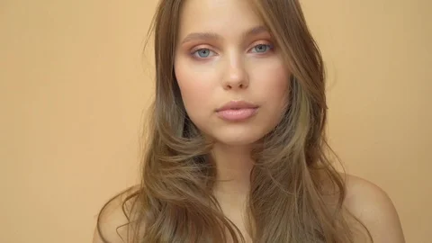 Closeup portrait of young wooman posing to a camera with blowed out hair on grey Stock Footage 114742023