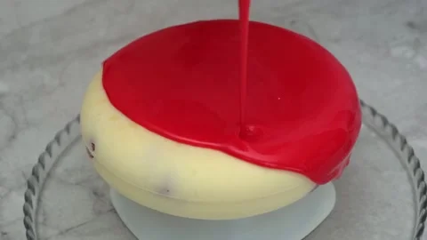 Closeup, pour liquid red glaze on cake, standing on a glass tray, the process of Stock Footage 148834894