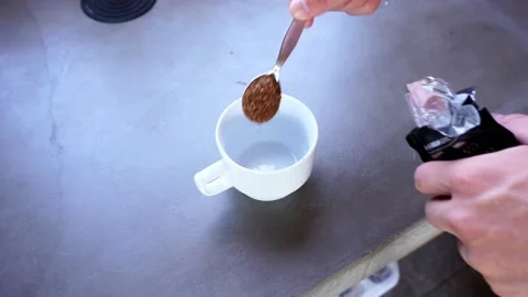 Closeup pouring coffee with spoon to empty white cup on concrete kitchen table a Stock Footage 199509598