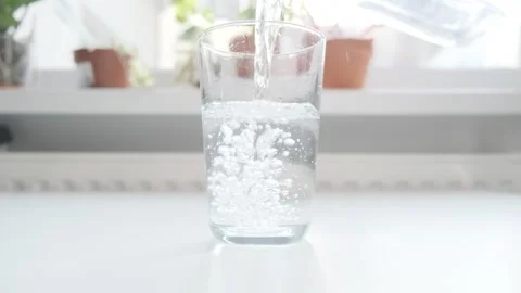 Closeup of pouring water with bubbles from a jug into glass. Blurry background. 스톡 동영상 265172035