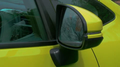 Closeup of a powered side-view / door mirror on a yellow car, opening out. Stock Footage 240210037
