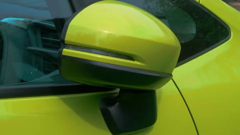 Closeup of a powered side-view / door mirror on a yellow car, closing in. Video stock 240210090