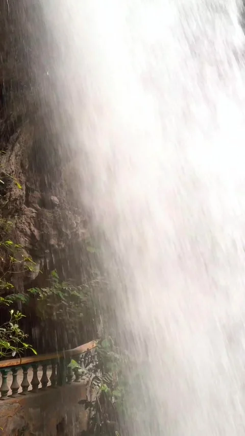 Closeup of Powerful Waterfall Flowing Down Rocky Cliff With Green Vegetation Stock Footage 346267322