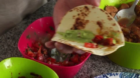 Closeup preparing tacos with avocado, meat and salad with his hands in the Stock Footage 194471200