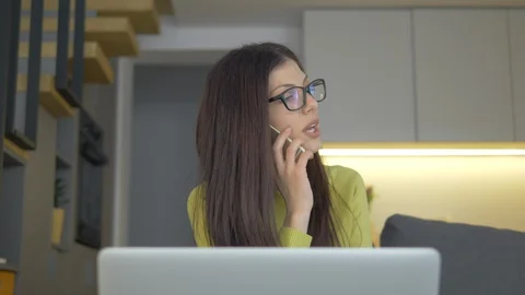 Closeup Of A Pretty Lady Working From Home, On А Laptop And Talking On Phone Video stock 128366339