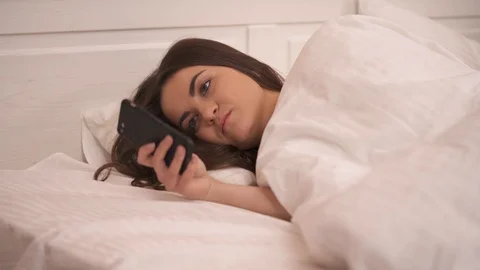 A closeup of a pretty long-haired brunette is lying sidelong in bed Stock Footage 101387765