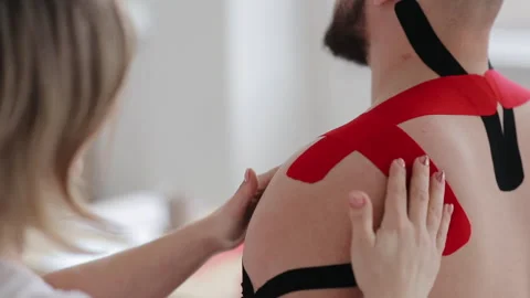Closeup Of Process Of Placing Kinesiology Tape On Man's Shoulder Stock Footage 130217855