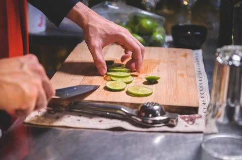 Closeup of professional bartender hand slicing lemon for making lemonade ju.. Stock Photos
