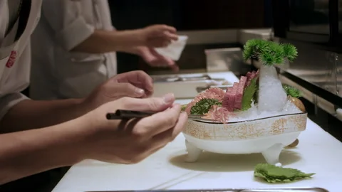 Closeup Professional chef hand preparing red salmon sashimi on ice on white Stock Footage 208880006