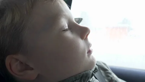 Closeup profile shot of 6 years old blond boy sleeping in car while driving Stock Footage 86297809