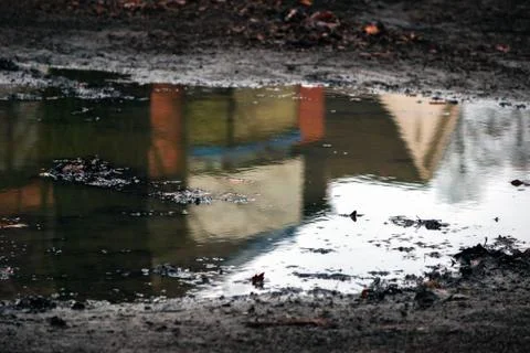 Closeup of puddle on the road, with reflection at home. Stock Photos