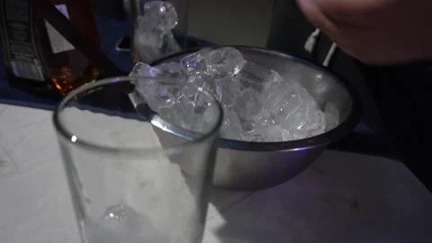 Closeup putting ice chunks by hand into glass cups at night party Stock Footage 170013825